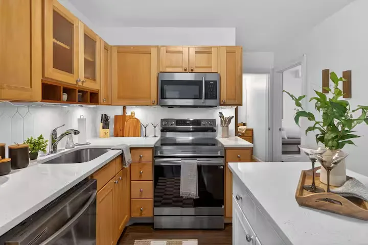 Bright white kitchen with dark counters and warm wood flooring
